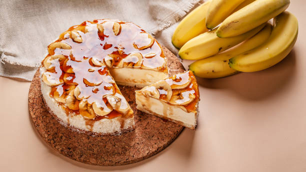 A delicious banana cake topped with caramel and sliced bananas, next to a bunch of fresh bananas.
