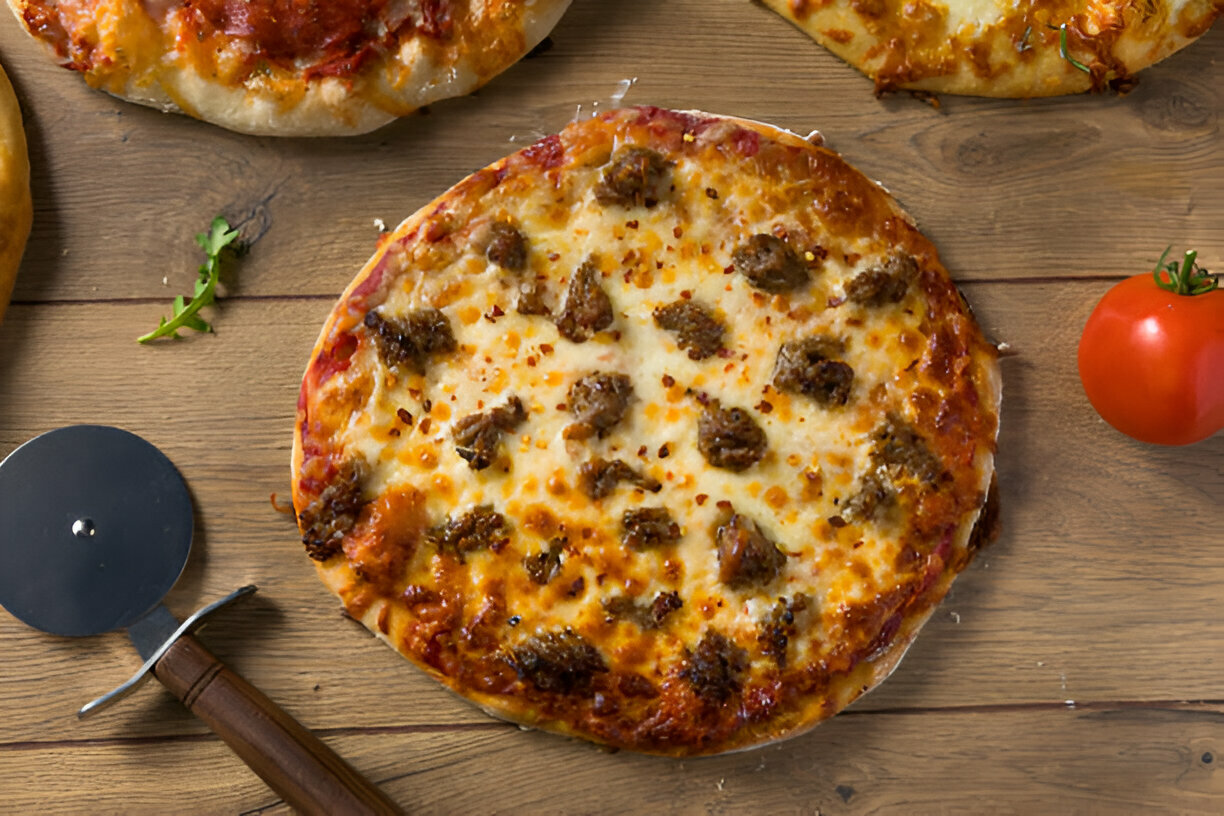 A freshly baked pizza topped with cheese and meat on a wooden table