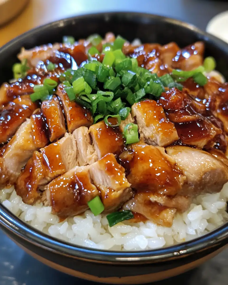 Plated honey BBQ chicken rice with garnish of chopped green onions