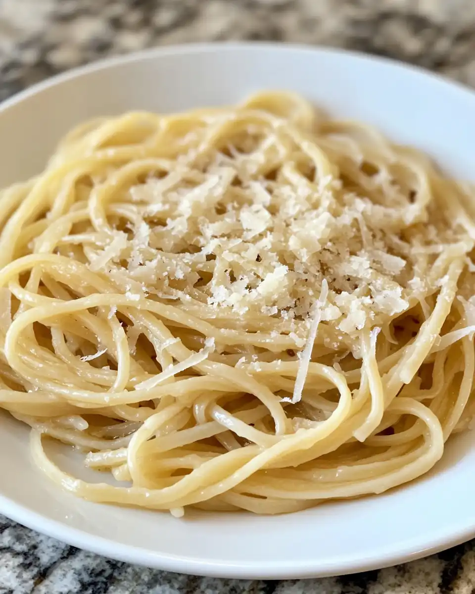 Close-up of finished caramelized onion pasta with grated cheese and olive oil