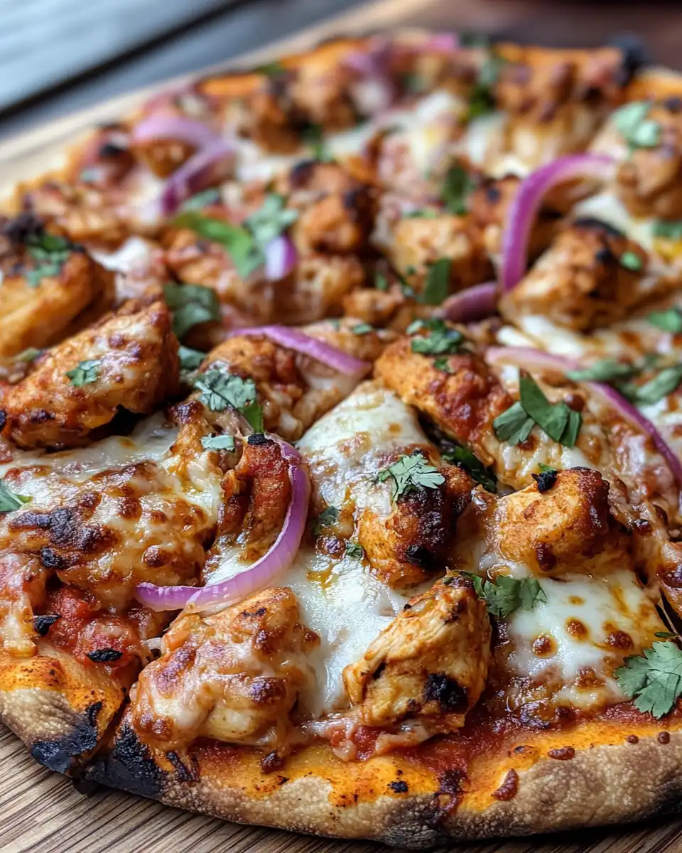 Layering tomato sauce and spices on naan bread for tandoori chicken pizza