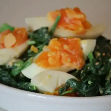 Close-up of Spinach Salad With Bacon And Eggs showing the texture and color detail